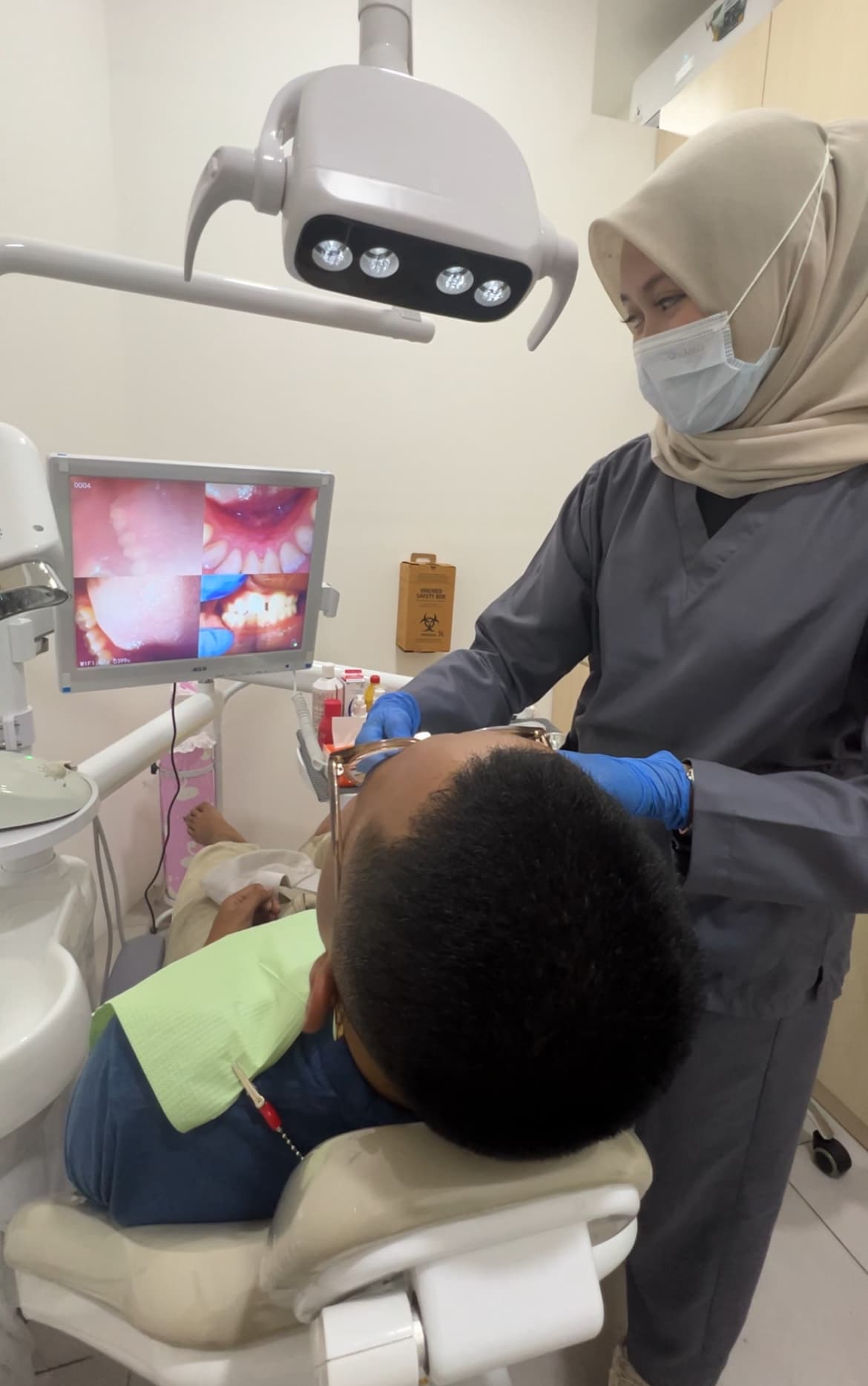 Dokter gigi Dental Rakyat merawat pasien di ruang tindakan klinik